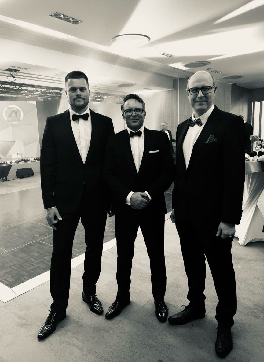 Three attendees in black tie at the gala